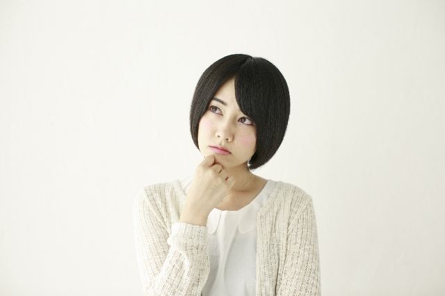 手を顎に置き首を傾げる女性